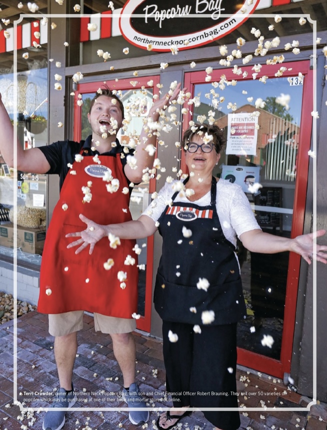 Photo of Terri and her son Rob in front of the popcorn store throwing popcorn up in the air